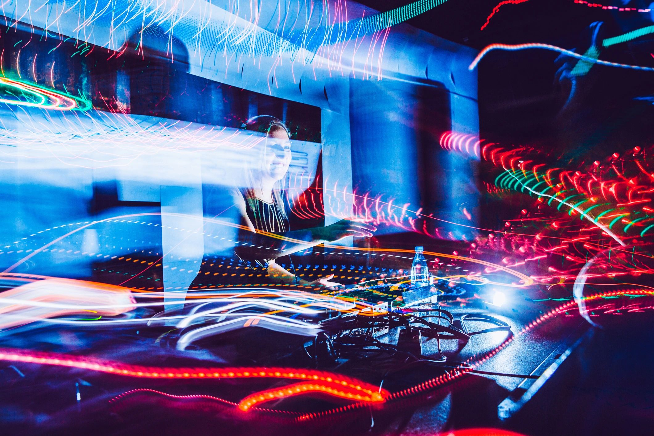 DJ performing at an electronic music event with neon lights